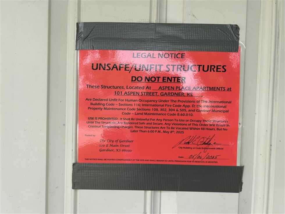 Picture shows a red and black notice taped to a white door of an apartment. The notice warns...