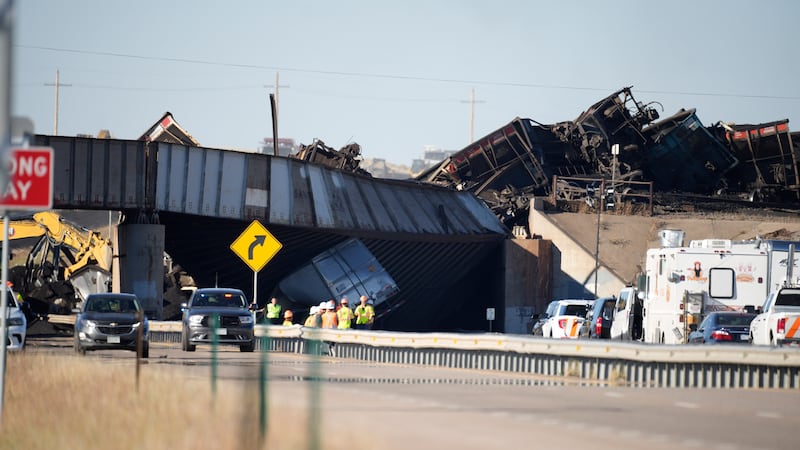 FILE - Workers toil to clear rail cars that derailed and collapsed a bridge over Interstate 25...
