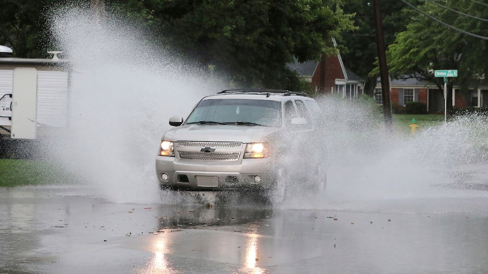 A motorist drives through some standing water along the 2100 block of Ford Avenue during the...