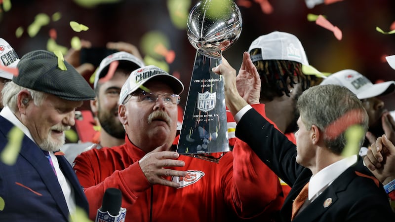 Kansas City Chiefs chairman Clark Hunt, right, hands the trophy to head coach Andy Reid after...