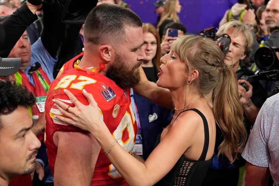 El tight end de los Chiefs de Kansas City Travis Kelce (87) habla con Taylor Swift después del...