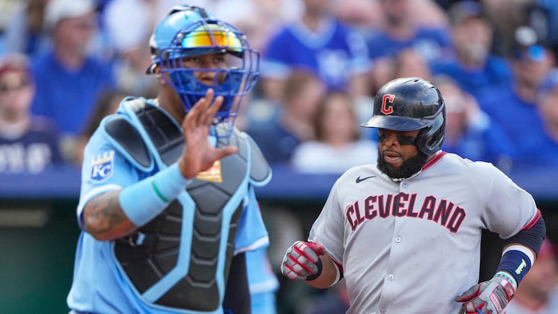 Cleveland Guardians' Carlos Santana runs past Kansas City Royals catcher Salvador Perez to...