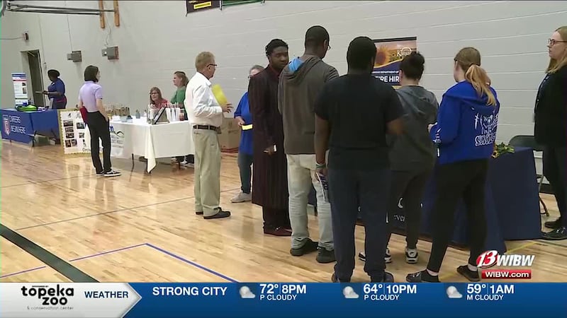 Young people at a career fair stand in line to learn more about a job.