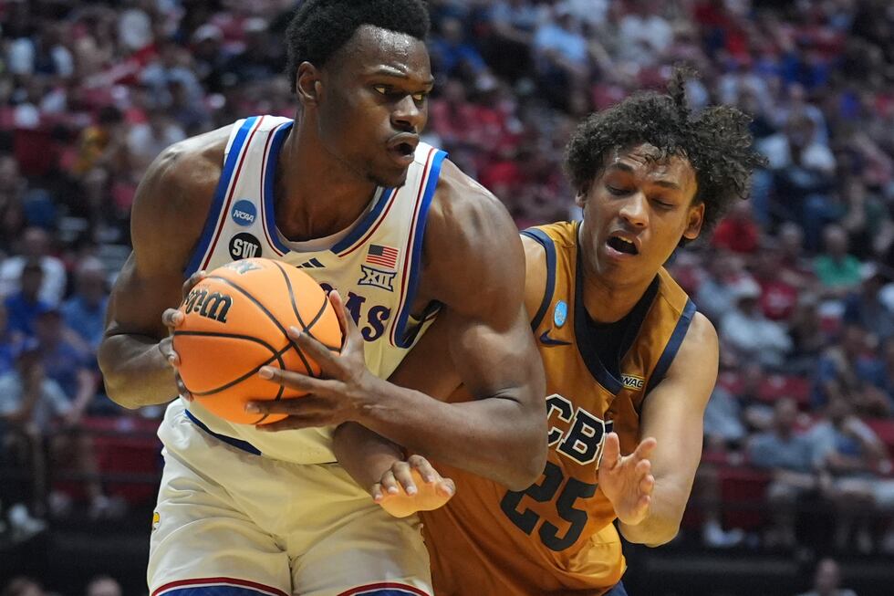 Kansas center Paul Mbiya, left, looks to pass as California Baptist forward Thomas Ndong...