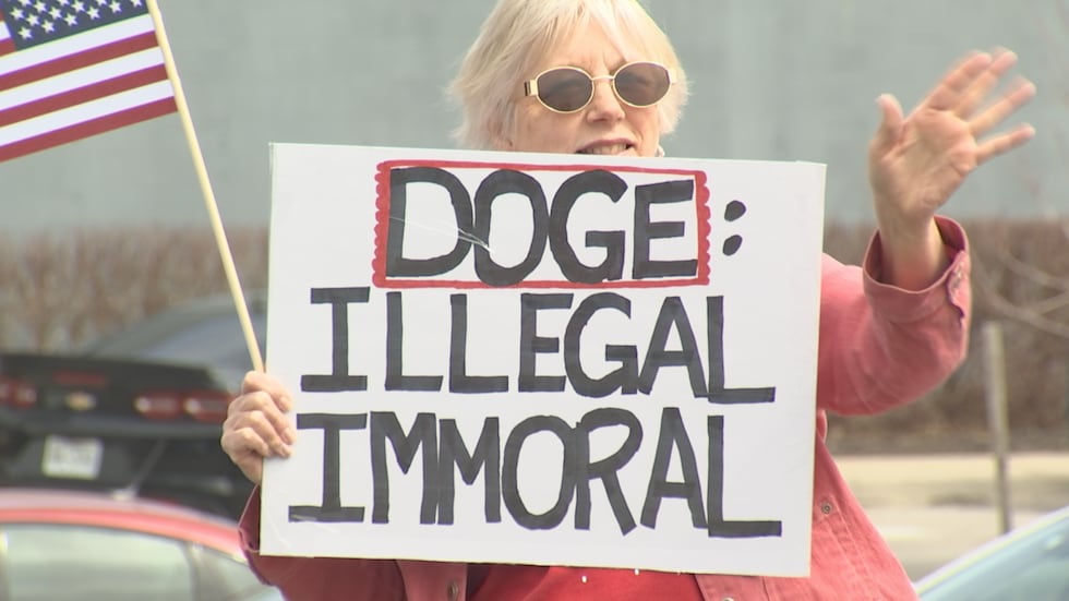 Demonstrators gathered near the Tesla dealership on State Line Road near 103rd Street to voice...