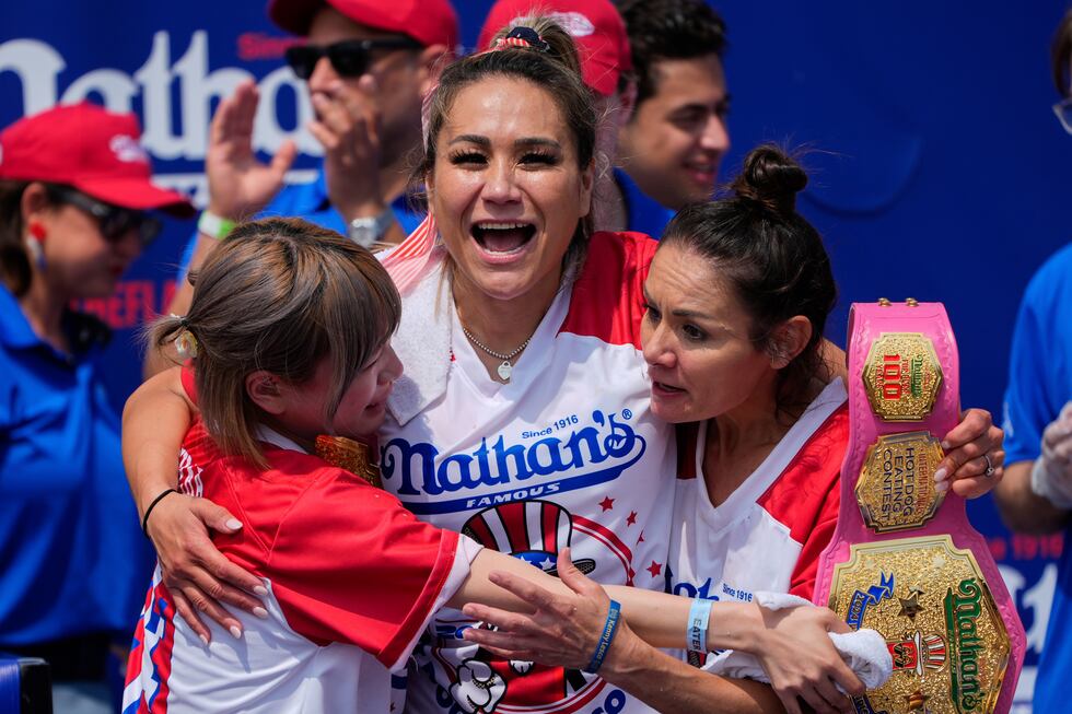Miki Sudo, center, hugs Mayoi Ebihara, left, and Michelle Lesco, right, after winning the...